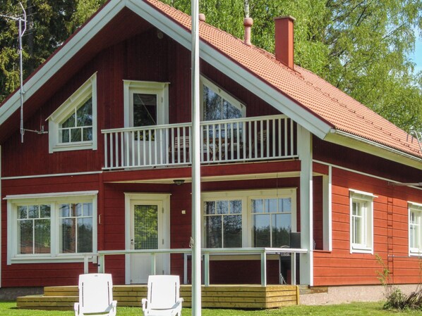 A two-story red house with a balcony, white railings, and a chimney.