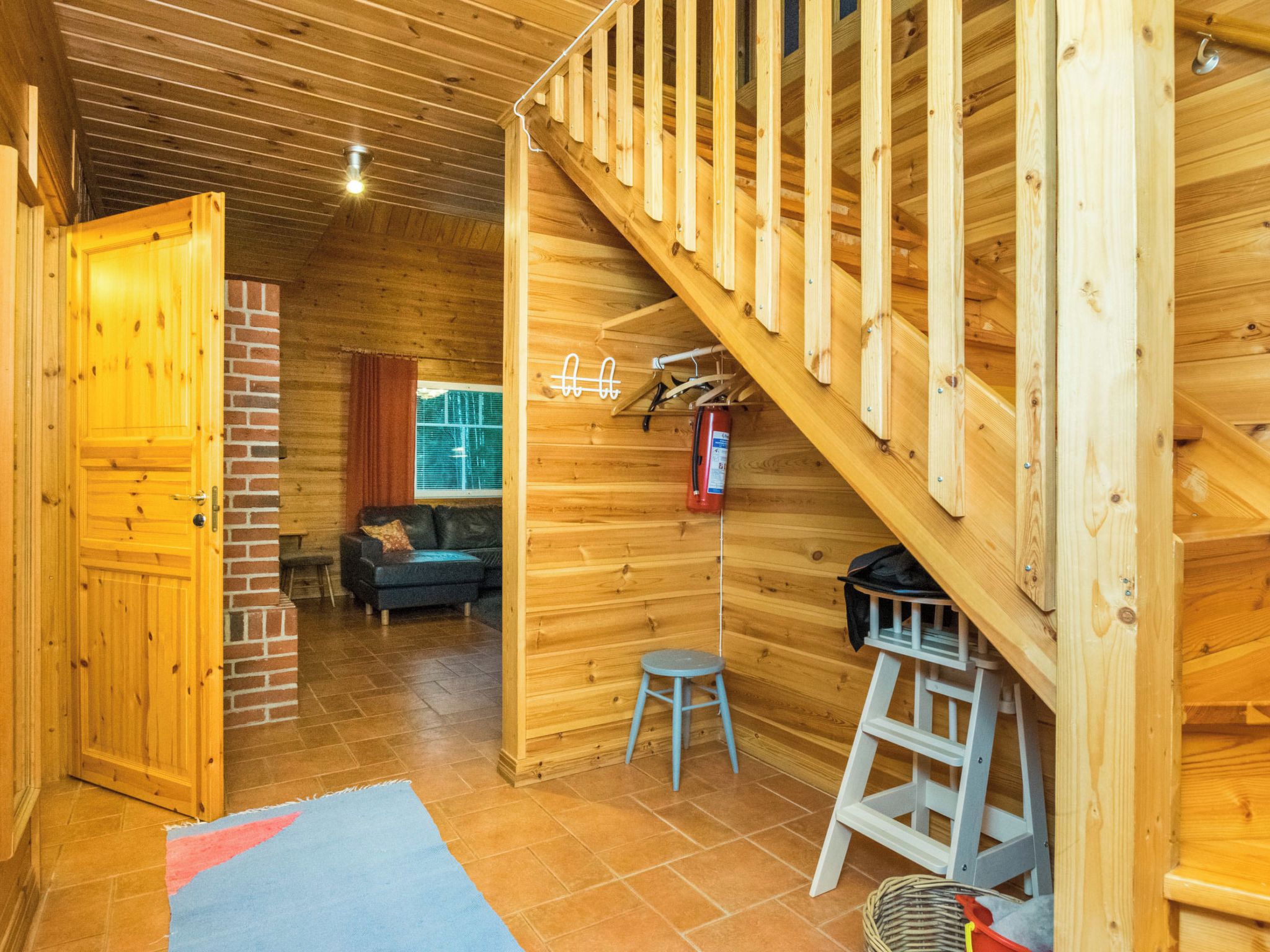 A wooden interior with a staircase, a sofa, and a small stool.