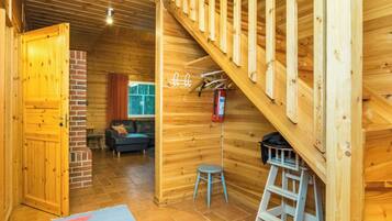 A wooden interior with a staircase, a sofa, and a small stool.