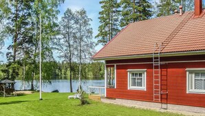 A red house with a tiled roof, a small deck, and a view of a lake.