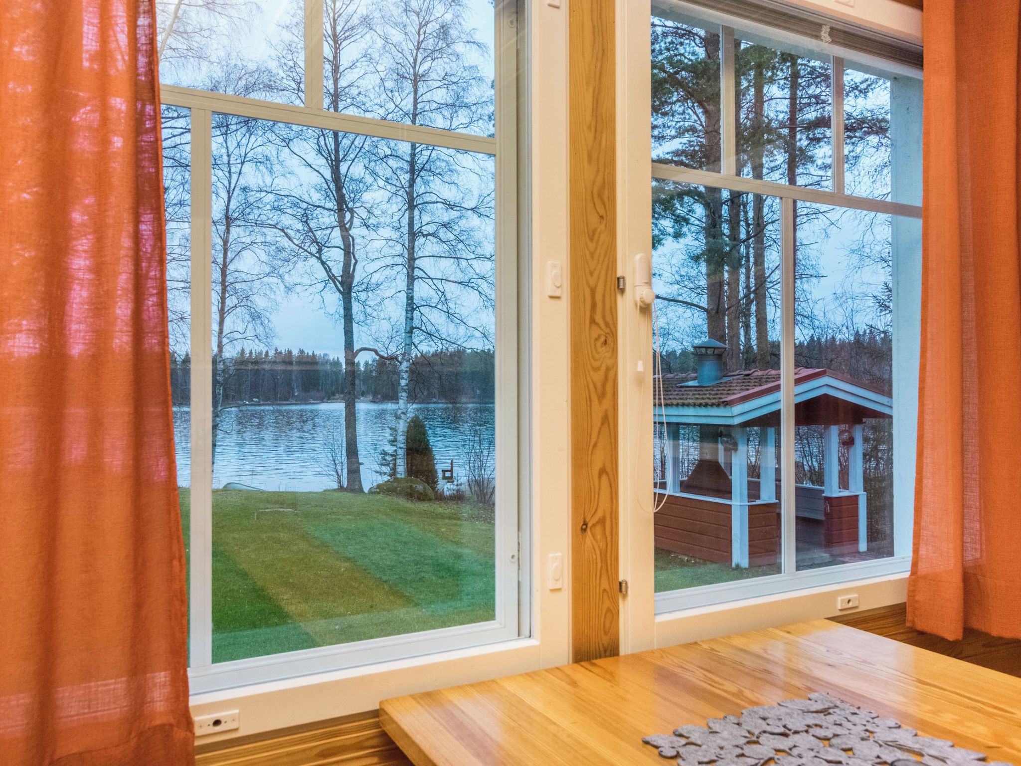 A room with a large window overlooking a lake and a dock.