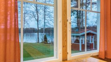 A room with a large window overlooking a lake and a dock.