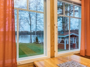 Een kamer met een groot raam met uitzicht op een meer en een steiger.