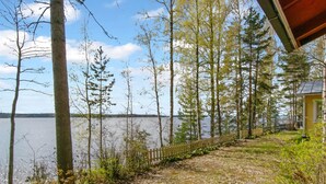 Une propriété au bord du lac, dotée d’une terrasse en bois, d’un chemin bordé de clôtures et d’un chalet avec un porche.