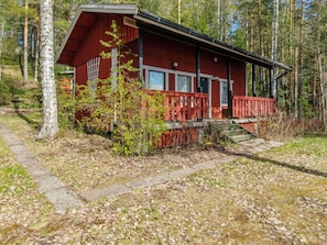 A red cabin with a porch and a stone pathway leading to it.