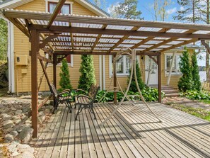 A wooden deck with a pergola, outdoor seating, and a house in the background.