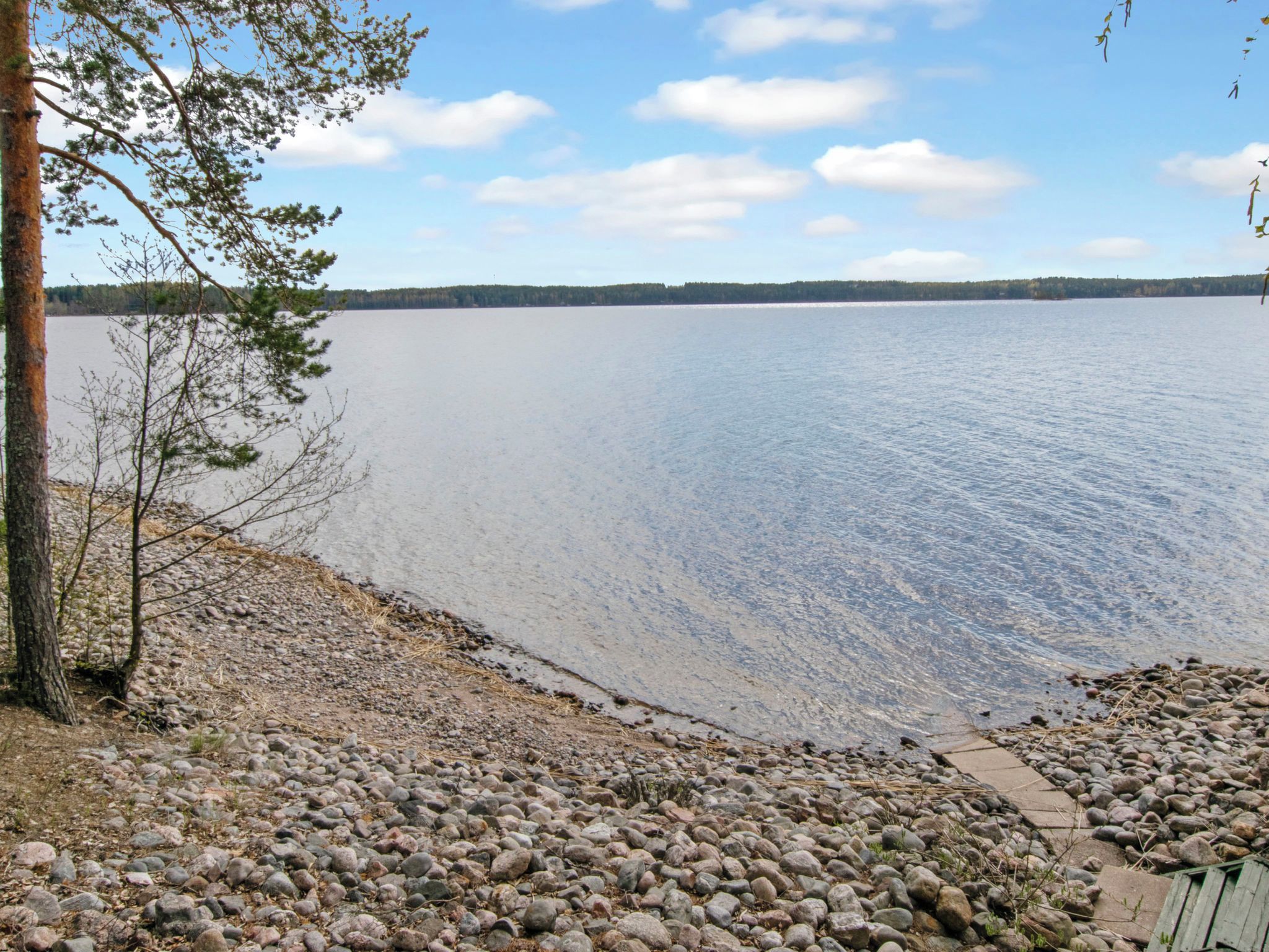 Ein See mit steiniger Uferlinie und blauem Himmel.