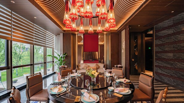 A modern dining area with a round table set for six, surrounded by comfortable chairs. - voco Hangzhou Binjiang Minghao by IHG (Hangzhou)