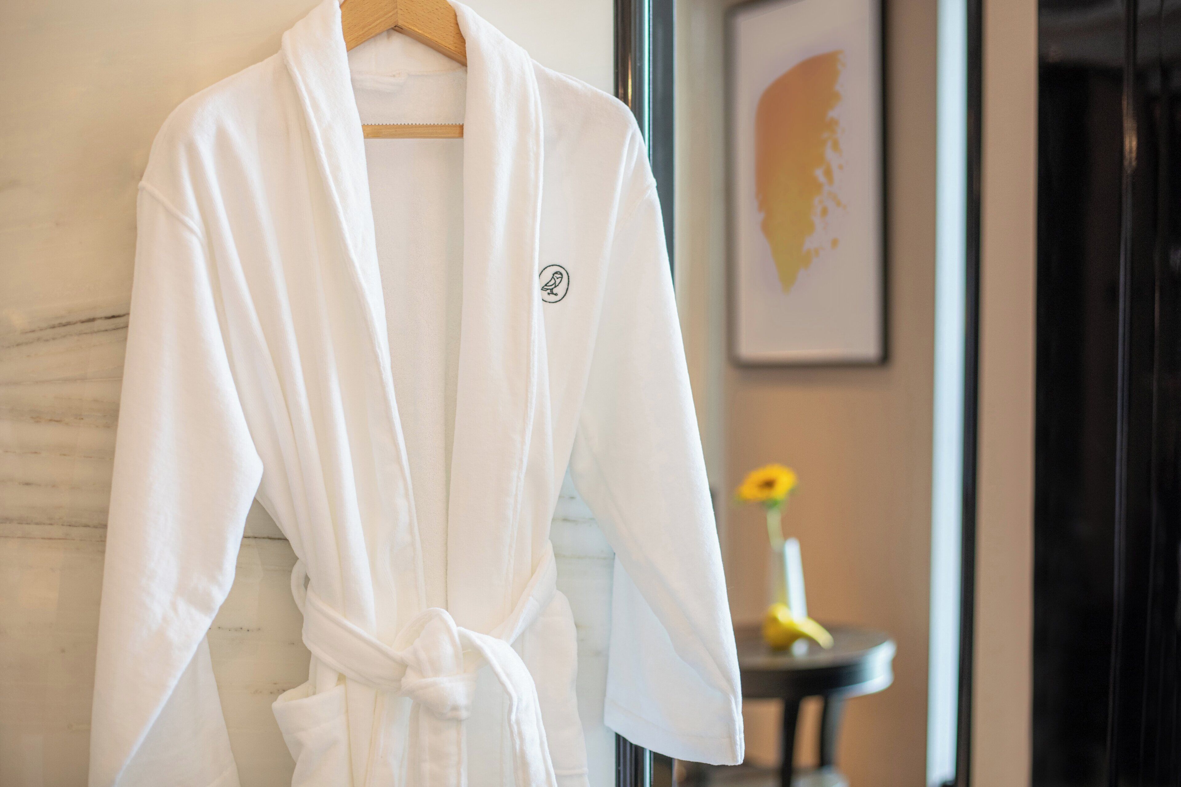 A white bathrobe hanging on a wooden hanger.