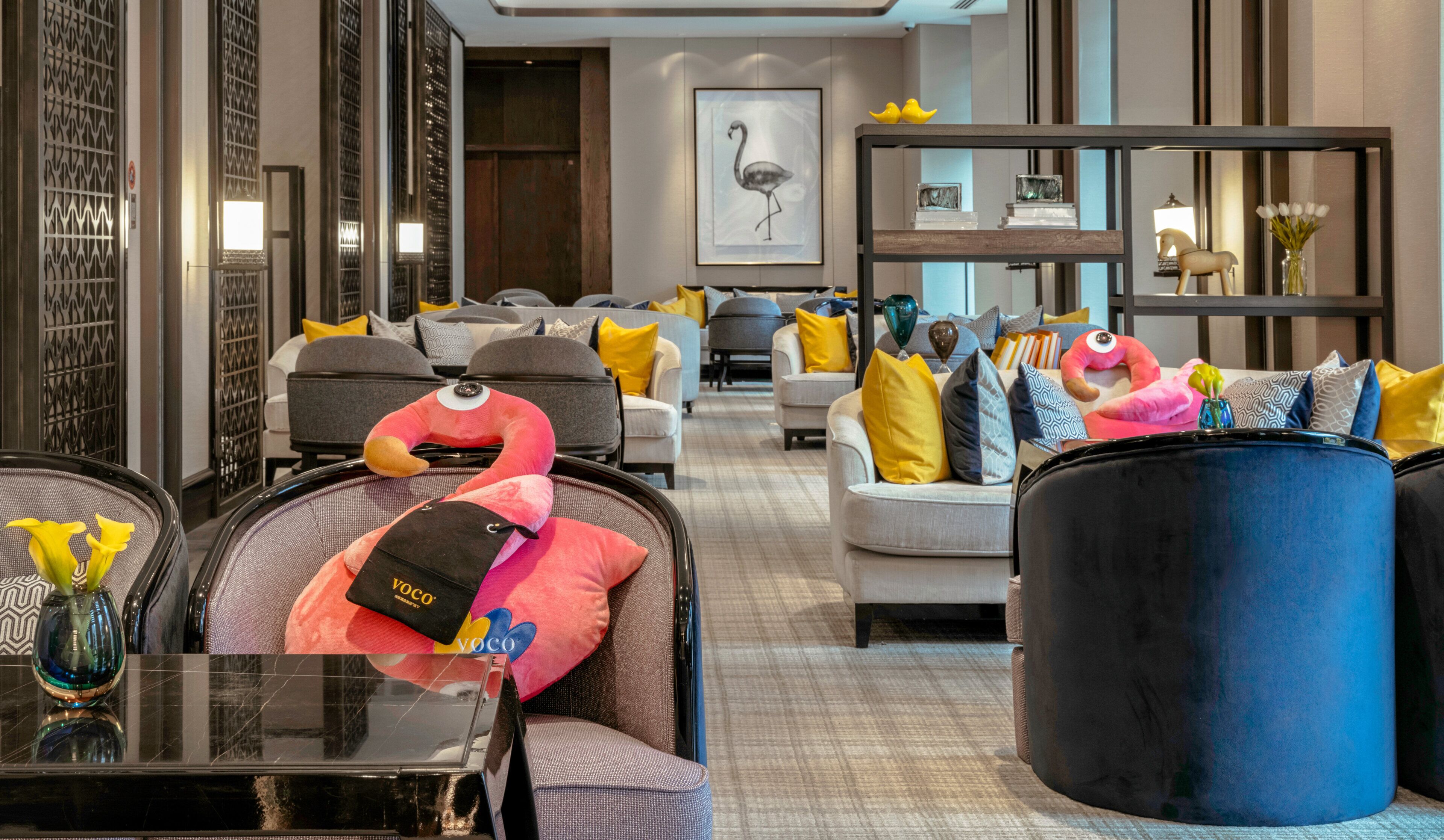 A hotel lobby with seating areas, a reception desk, and a large framed artwork on the wall.