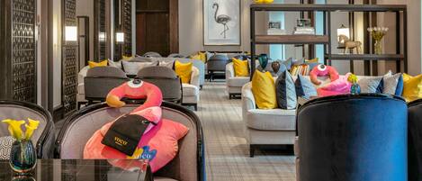 A hotel lobby with seating areas, a reception desk, and a large framed artwork on the wall.