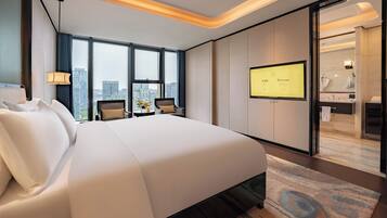 Una habitación de hotel moderna con una cama grande, un escritorio con silla, televisión y vistas a la ciudad.