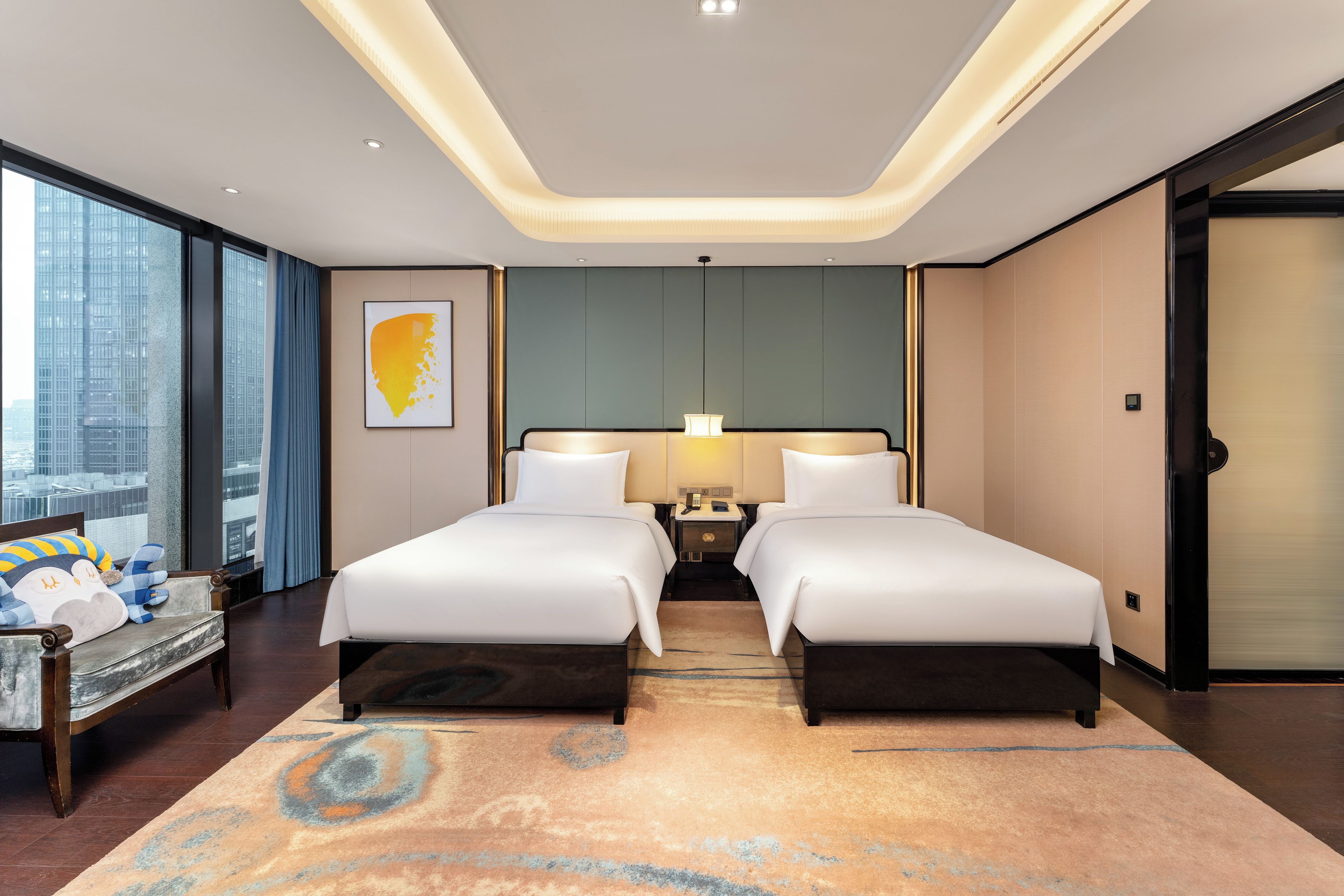 A modern hotel room with two beds, a large window, and a city view.