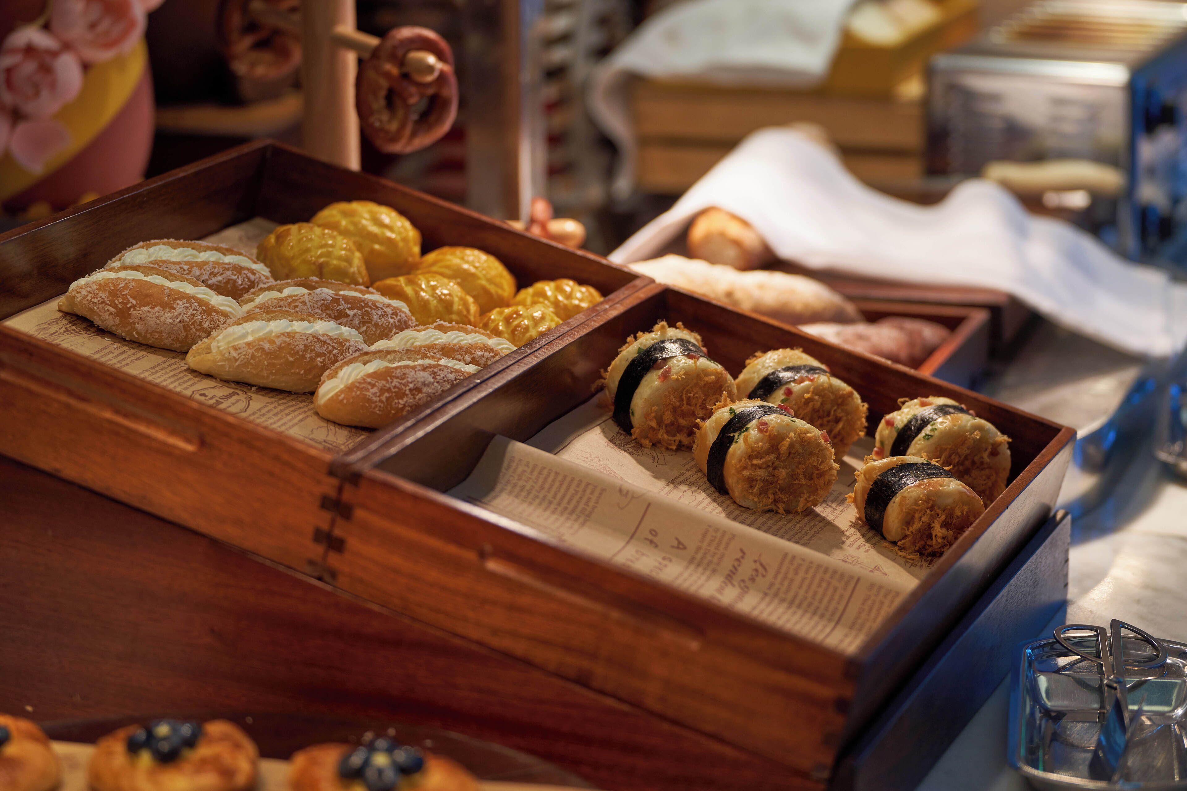 A wooden tray with pastries and sushi rolls.
