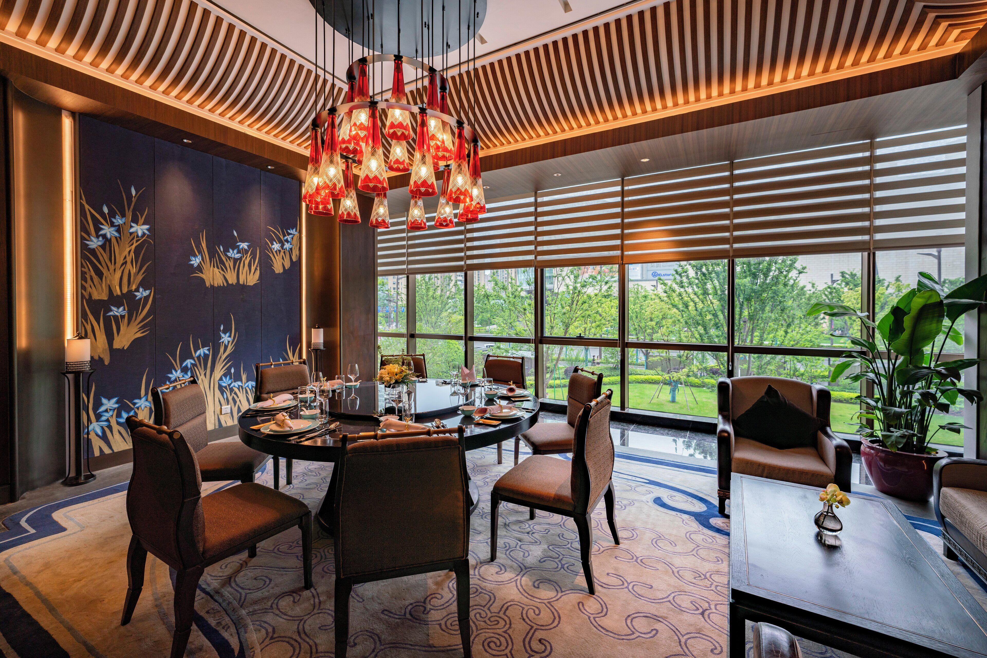 A modern dining area with a round table, chairs, and a chandelier.