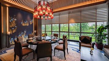 A modern dining area with a round table, chairs, and a chandelier.