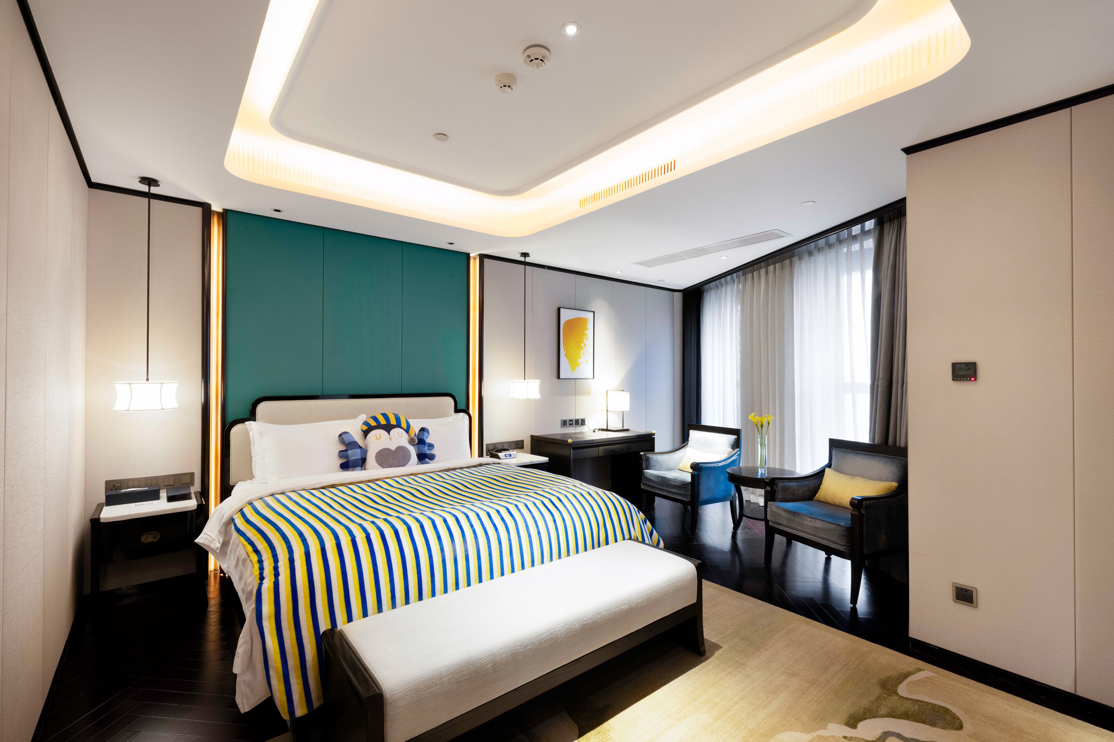 Habitación de hotel moderna con una cama grande, un escritorio, una silla y vistas al exterior.