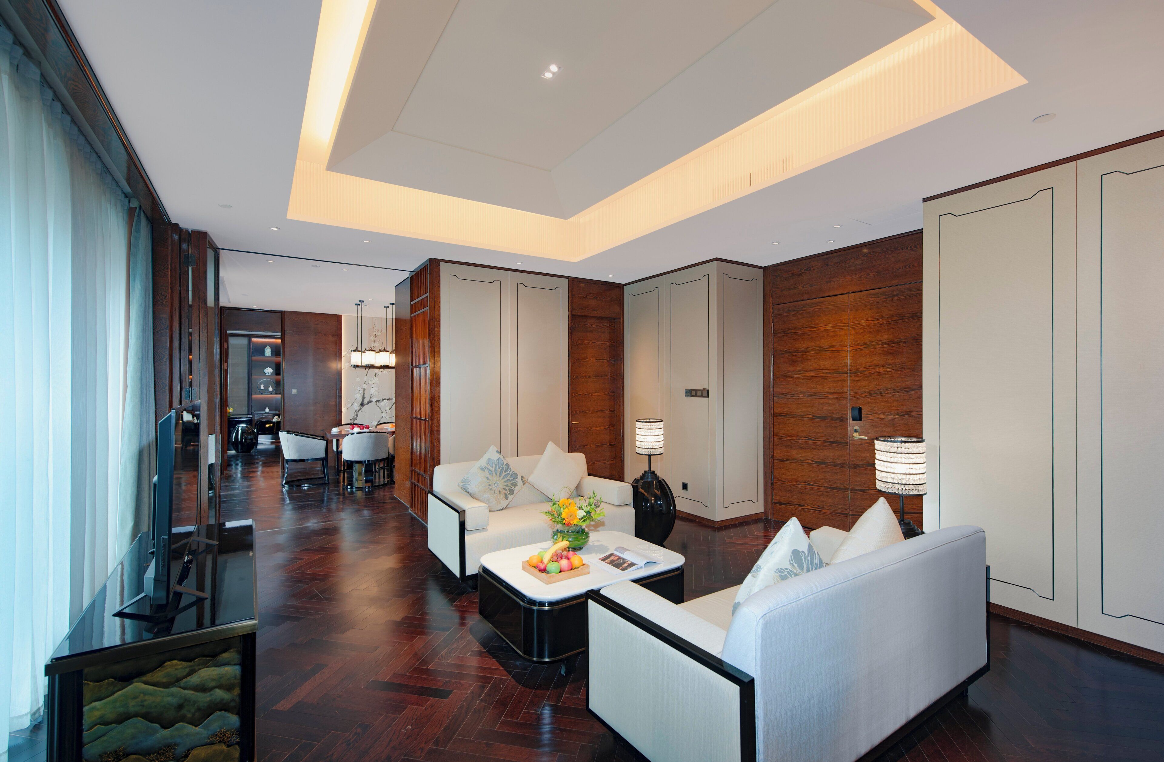A modern hotel lobby with a sofa, coffee table, and dining area.