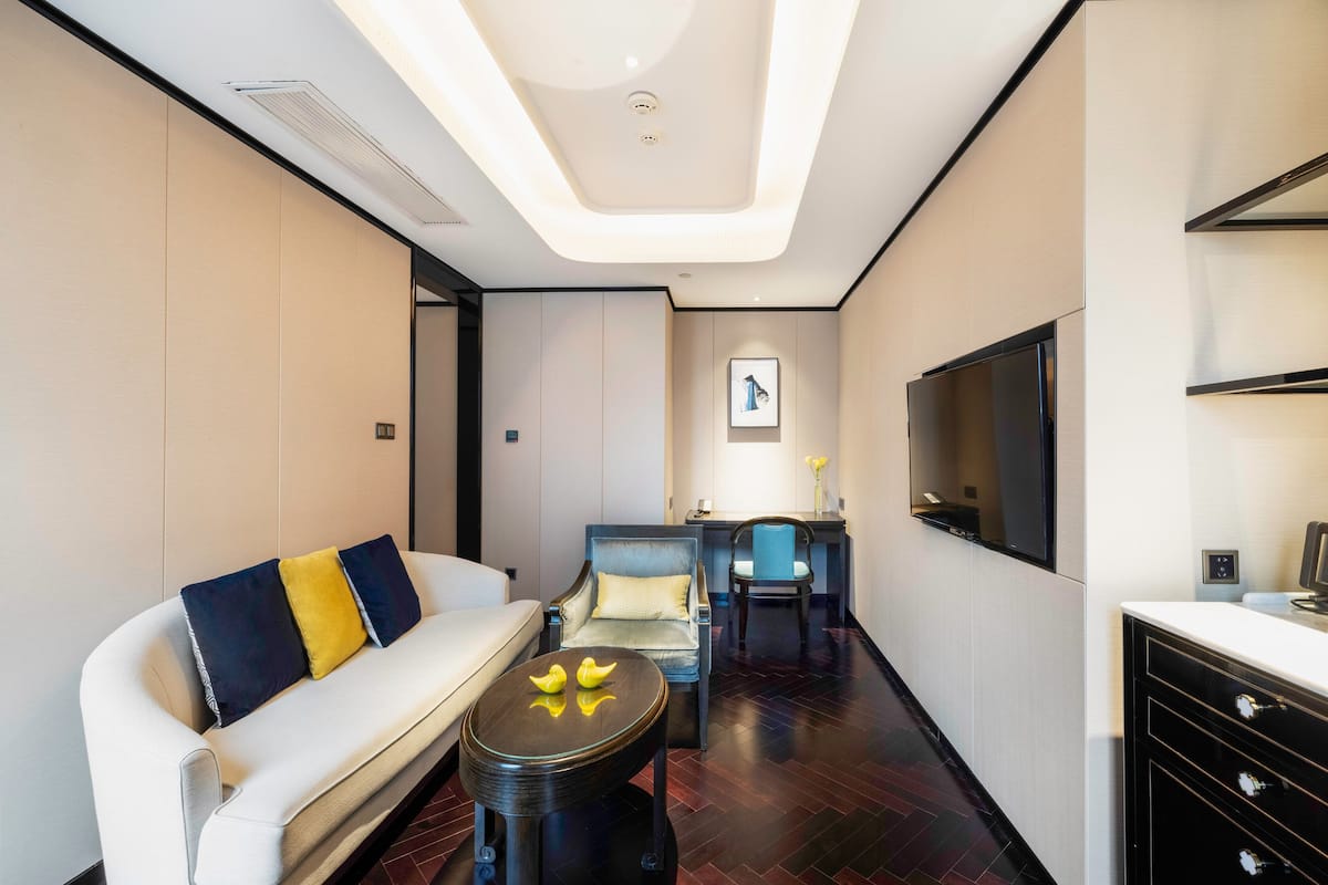 Une chambre d’hôtel moderne, dotée d’un canapé, d’un fauteuil et d’une petite table ronde agrémentée d’objets décoratifs.