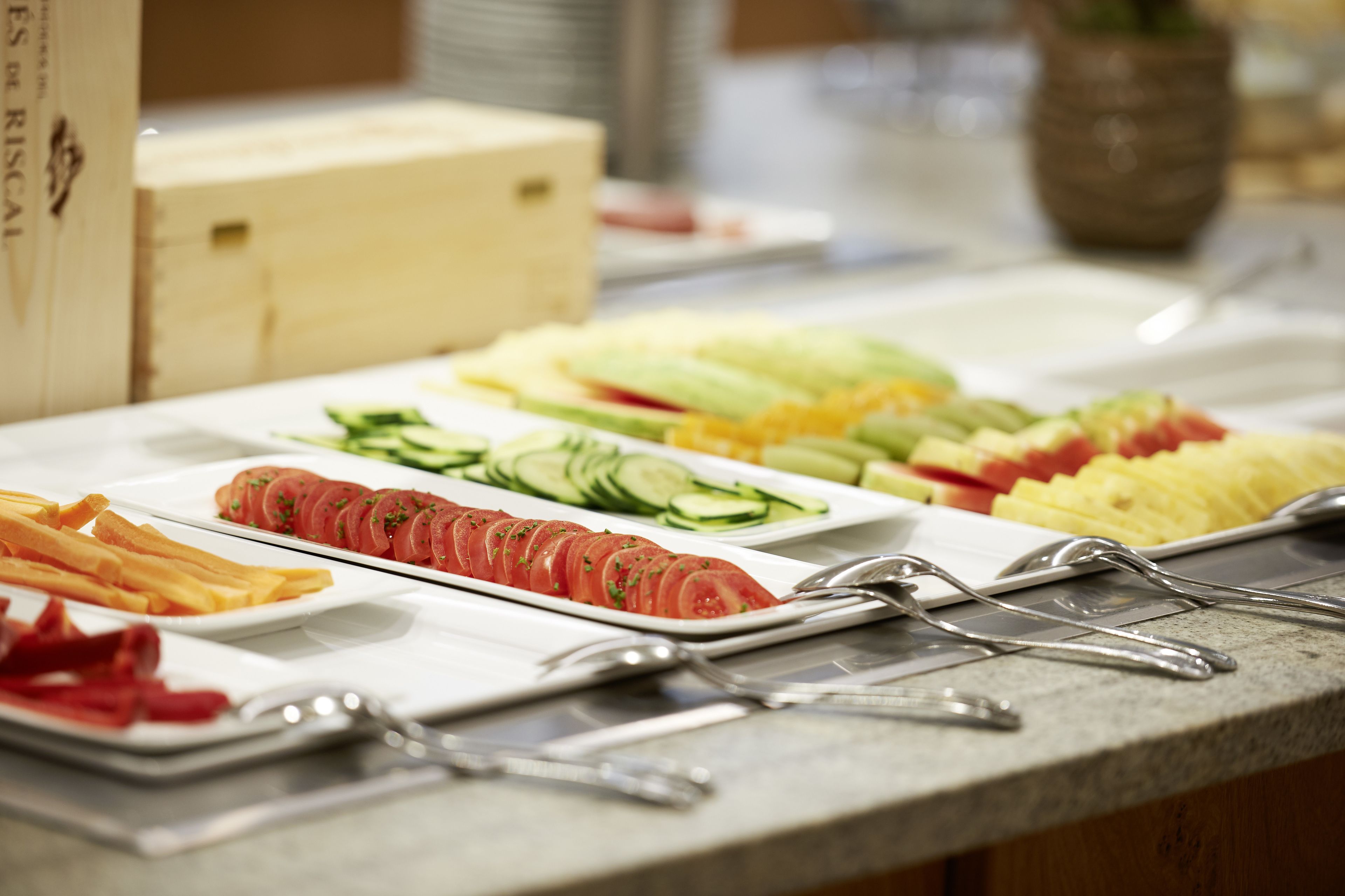 Een buffet met diverse etenswaren, waaronder plakjes tomaat, komkommer en ander groenteproduct.