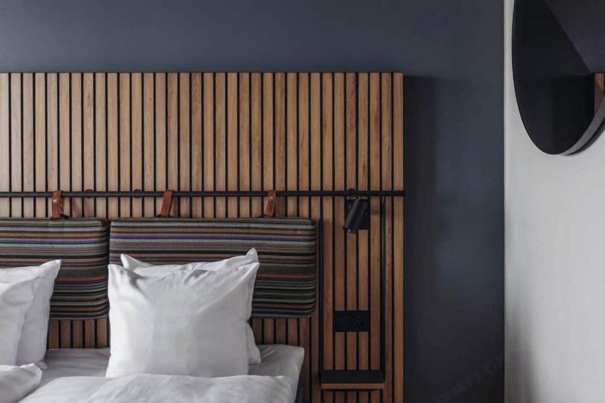 Una cama con cabecera de madera, dos almohadas y una almohada a rayas.