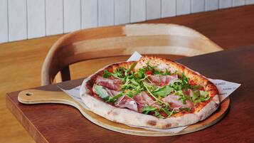 A pizza on a wooden board with a handle, placed on a table.