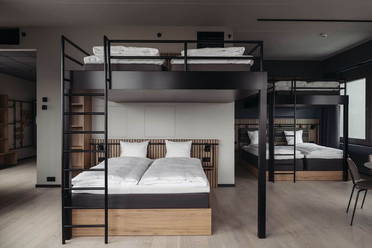 Habitació moderna amb lliteres de diversos nivells, amb panells decoratius de fusta i un escriptori integrat.