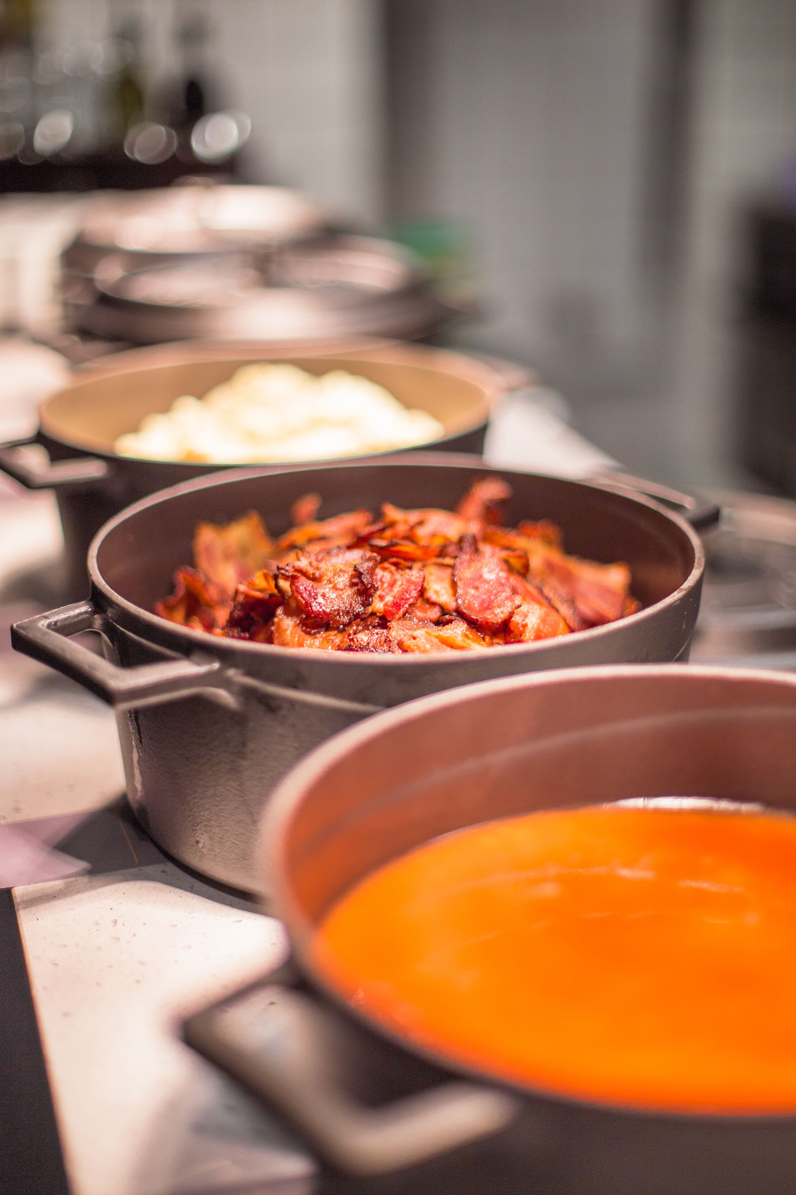 A table with various dishes, including a bowl of soup and a dish with bacon.