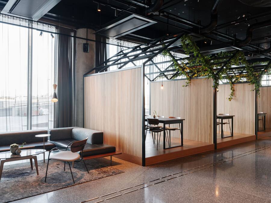 Un interior moderno con un sofá, sillas, una mesita y un comedor con mesa y sillas.