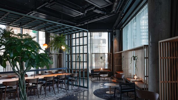 A modern interior with high ceilings, exposed ductwork, and large windows.