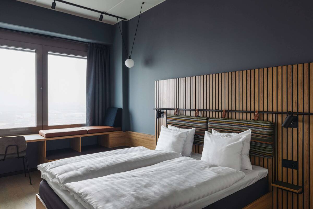 Habitació d'hotel moderna amb un llit gran, un escriptori i vista a la ciutat.