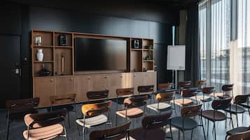 Un salón de conferencias con una pantalla grande, armarios de madera y varias sillas dispuestas para reuniones.