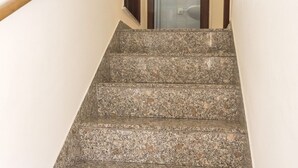 Eine Treppe mit Granitschrittsteinen, die zu einem Raum mit Glastür führt.