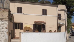 Ein Gebäude mit weißer Fassade, braunen Fensterläden und einem Ziegeldach.
