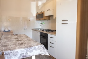 A kitchen with a stove, oven, microwave, and a refrigerator.
