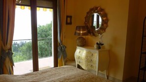 A bedroom with a bed, a dresser, a mirror, and a window with curtains.