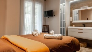 Quarto de hotel moderno com uma cama grande, televisão na parede e banheiro com espelho e pia.