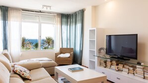 Uma sala de estar com sofá, mesa de centro, televisão e estante de livros.