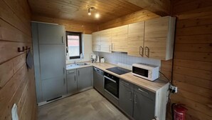 Una cocina compacta con paredes y armarios de madera, horno integrado y microondas.