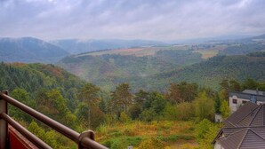 Et panorama over et bjerglandskab med et hus i forgrunden.