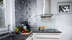 A modern kitchen with a stainless steel sink, white cabinets, and a patterned backsplash. - Kegelrobbe by Interhome (Norddeich)