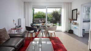 A modern living room with a glass coffee table, a leather sofa, and a dining area with a glass table and chairs. - Kegelrobbe by Interhome (Norddeich)