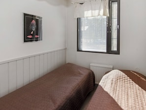 Una habitación pequeña con una cama individual, un radiador, una ventana con persianas y un cuadro en la pared.