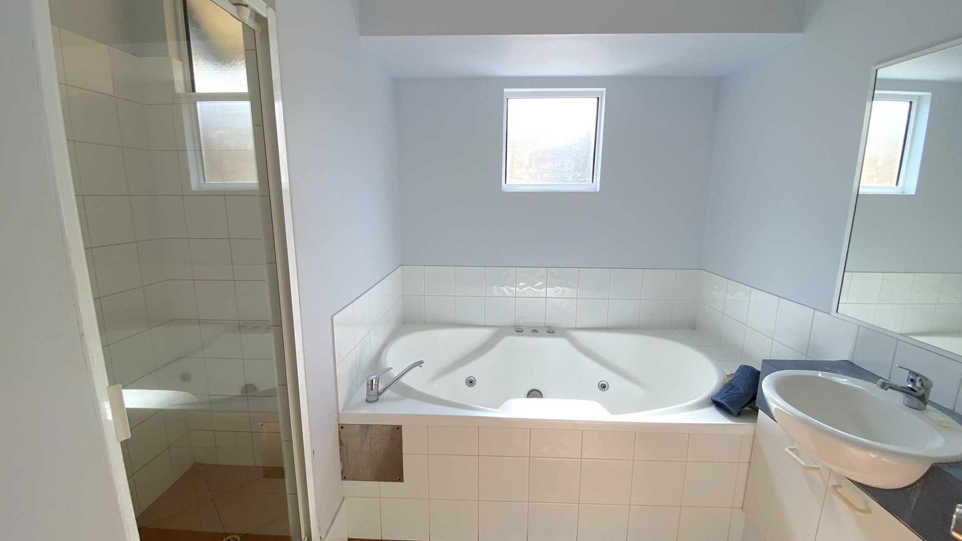 A bathroom with a bathtub, a sink, and a shower area.