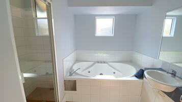 A bathroom with a bathtub, a sink, and a shower area.