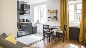 A compact kitchen with modern appliances, a dining area with a table and chairs, and a window with curtains.