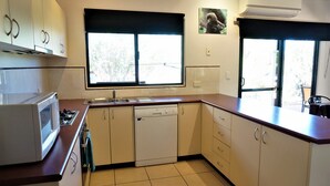 Cocina compacta con lavavajillas, estufa y ventana con vistas al verdor.