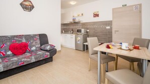 A modern hotel room with a sofa, a dining table, and a kitchenette.