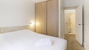 A hotel room with a bed, a wardrobe, and a bathroom visible through an open door. - Bright and comfortable apartment - 2nd FLOOR (BORDEAUX)