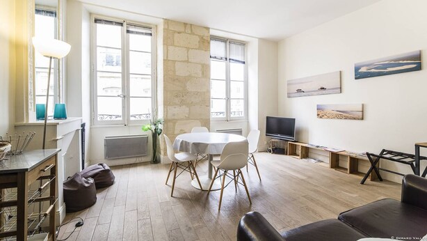 A modern living room with a dining area, large windows, a flat-screen TV, and artwork on the walls. - Bright and comfortable apartment - 2nd FLOOR (BORDEAUX)